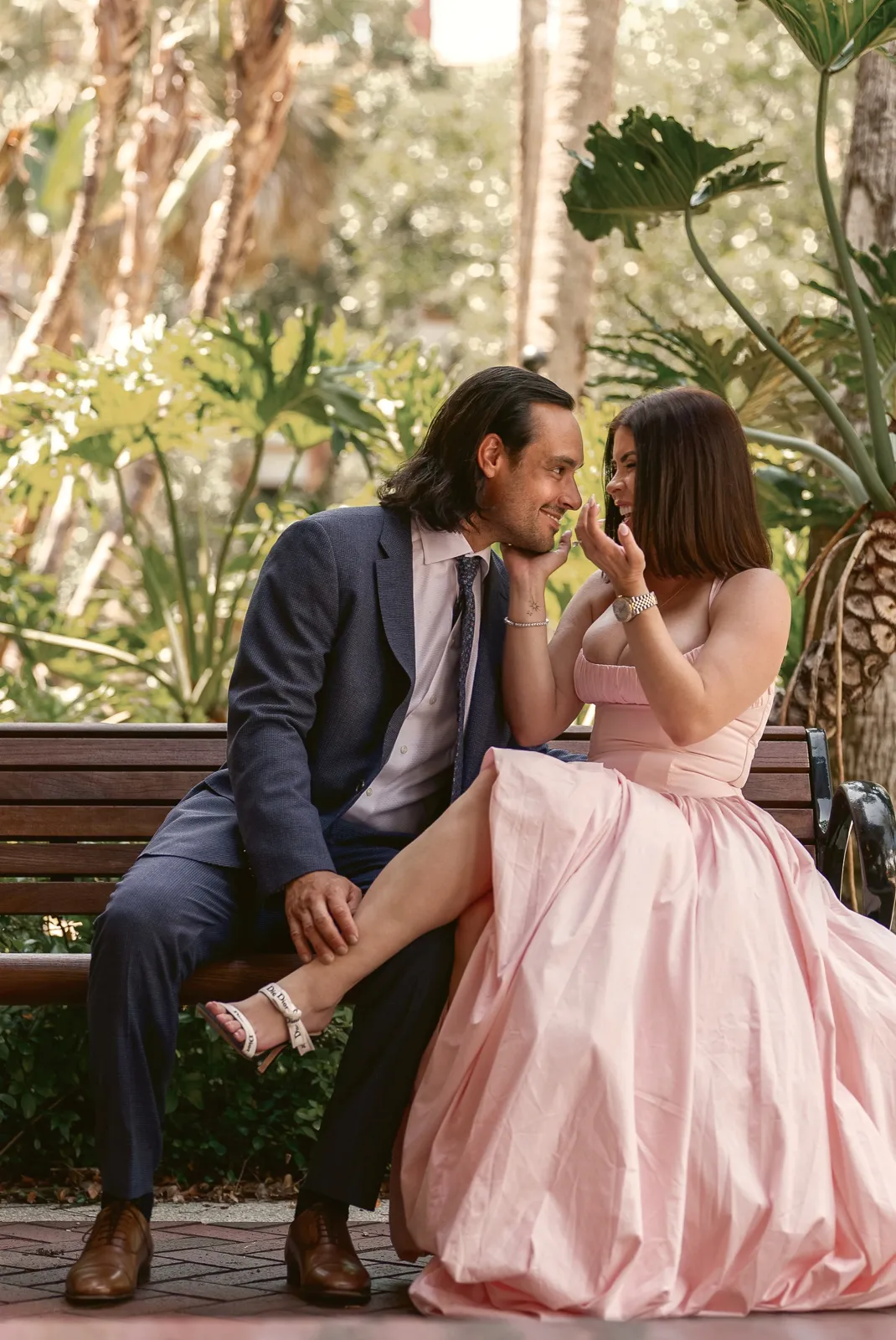 A woman laughing on a garden bench as her partner looks at her