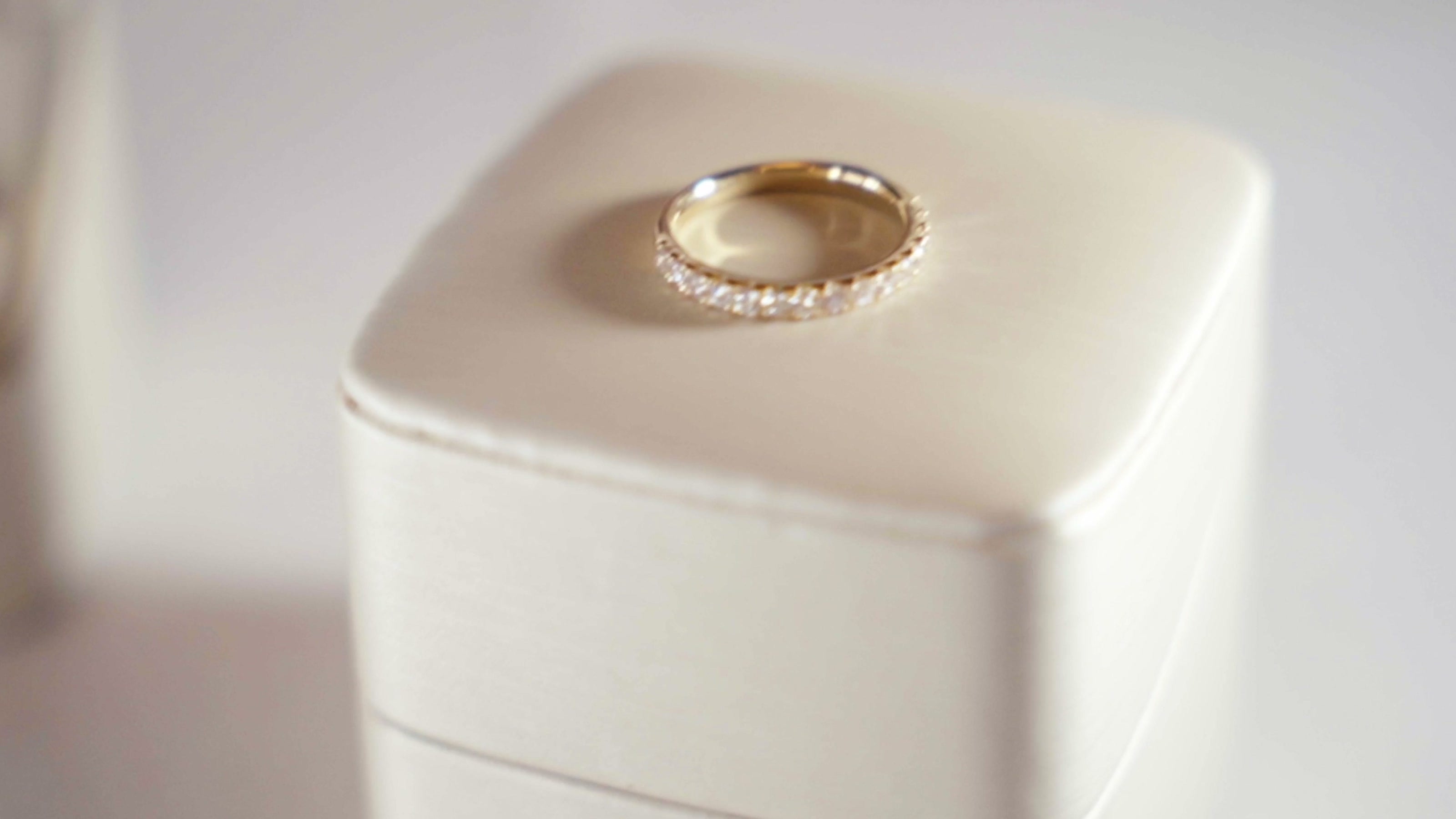 A wedding ring resting on a pale ring box